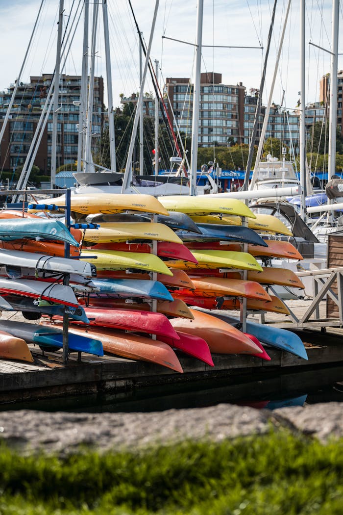 services-03 A stack of brightly colored kayaks in a bustling marina setting, perfect for outdoor water sports enthusiasts.